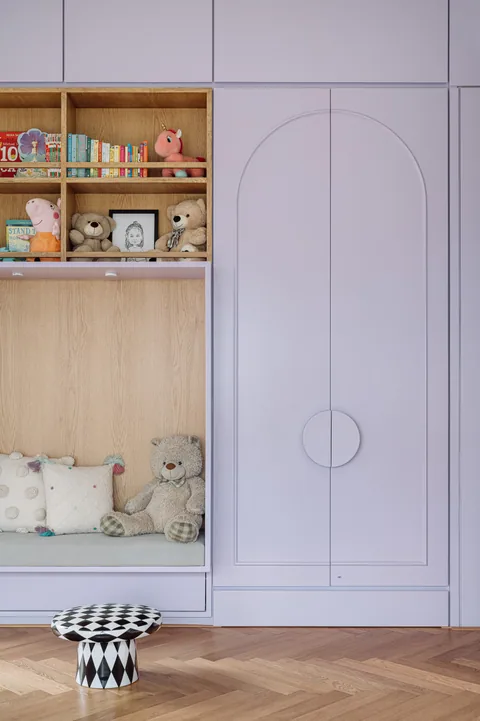 A Mumbai apartment storage wall with lilac wardrobe shutters, arched detailing and open timber shelves