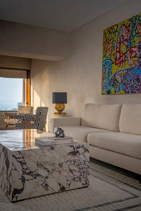 A South Mumbai living room with a sculptural veined-marble table, ivory upholstery and colourful art