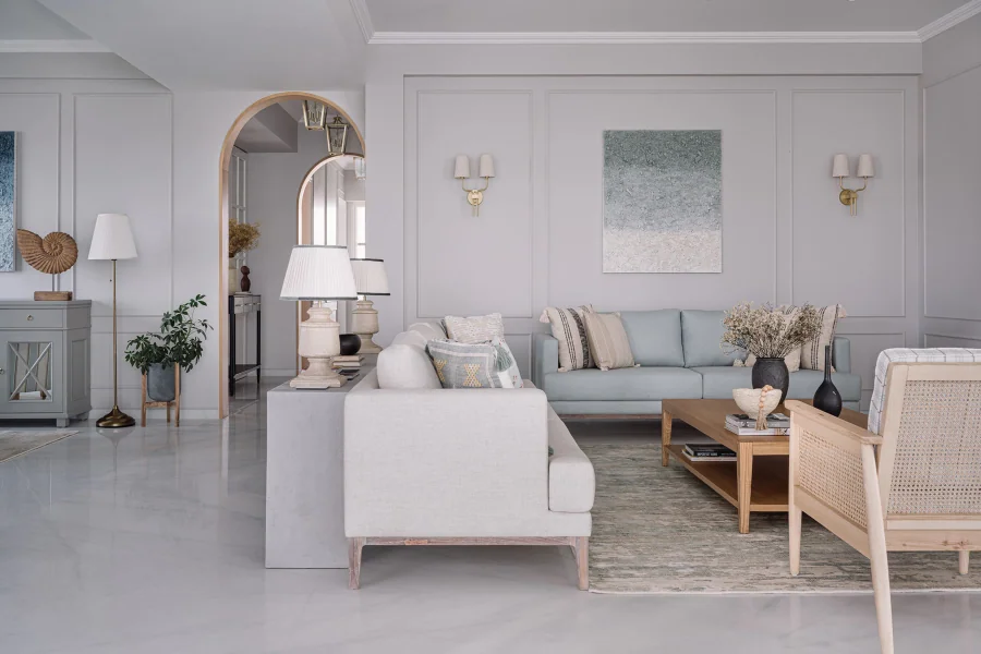 A real Mumbai apartment living room with pale blue and ivory sofas, cane armchairs, stone flooring and arched details